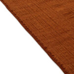 Detail van het Elitis Tenere vloerkleed TA 126 37 in warm roestbruin met subtiele textuur en afgewerkte rand.