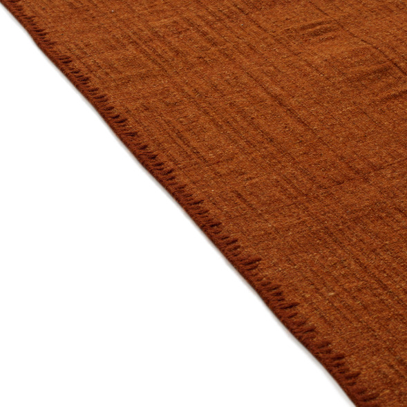 Detail van het Elitis Tenere vloerkleed TA 126 37 in warm roestbruin met subtiele textuur en afgewerkte rand.