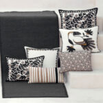 Zwarte Elitis Tenere TA 126-vloerkleed met decoratieve kussens in neutrale tinten en botanische patronen.
