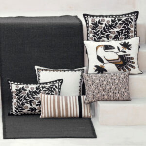 Zwarte Elitis Tenere TA 126-vloerkleed met decoratieve kussens in neutrale tinten en botanische patronen.