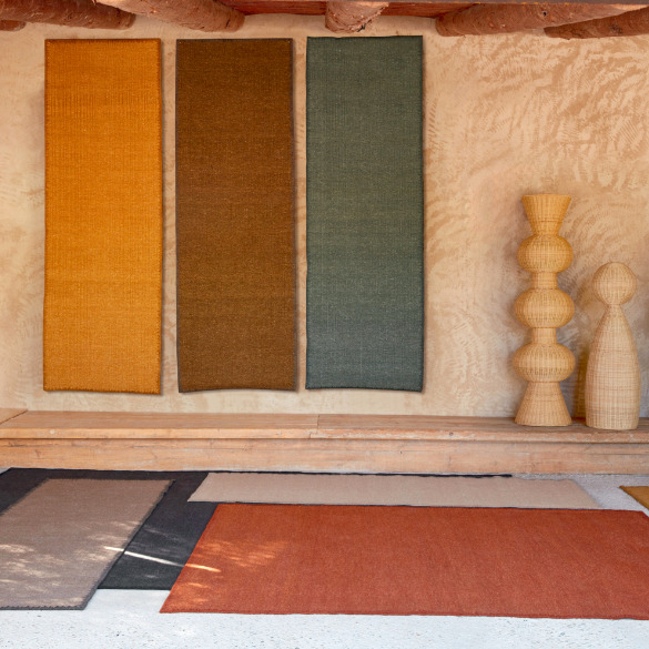Sfeervolle ruimte met Elitis Tenere TA 126 vloerkleden in warme kleuren aan de muur en op de vloer.