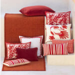 Rood Elitis Tenere TA 126 vloerkleed met daarop en ernaast sierkussens in rood-witte patronen.