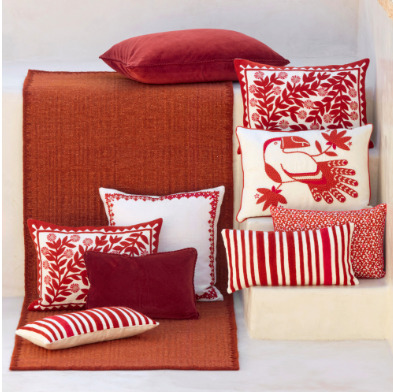 Rood Elitis Tenere TA 126 vloerkleed met daarop en ernaast sierkussens in rood-witte patronen.