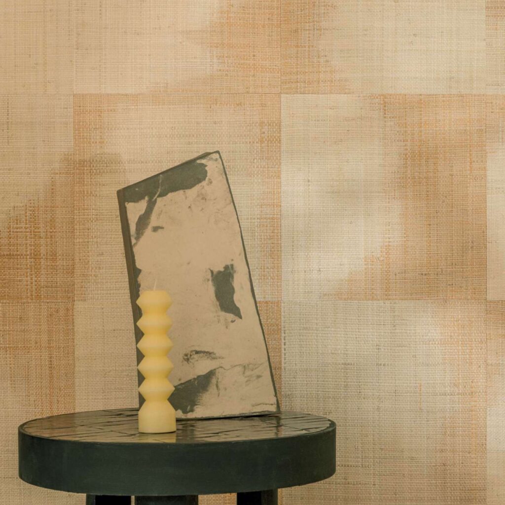 Detail van Elitis Tribus Comporta RM 1079-01 behang met een tafeltje, abstract kunstobject en gekartelde kaars.