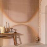 Sfeervolle interieurhoek met Elitis Tribus Itza RM 1081 04 behang in aardetinten, houten tafel en decoratieve objecten.