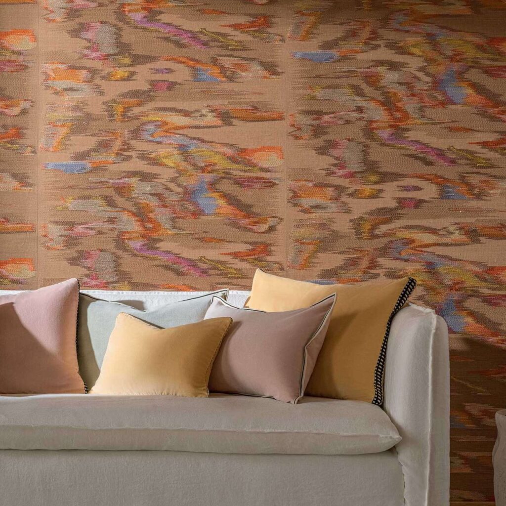 Woonkamer met Elitis Tribus Samarkand RM 1098 15 wandbekleding en zachte kussens op een lichte bank.