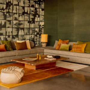 Moderne woonkamer met een Elitis vloerkleed Celeste TA 133 25 02 in warme aardetinten onder een houten salontafel en een hoekbank met gekleurde kussens.