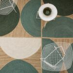 Wit metalen stoelen en een tafeltje staan op het grafisch geweven Elitis vloerkleed Rocky Sauge in groen- en natuurtinten.