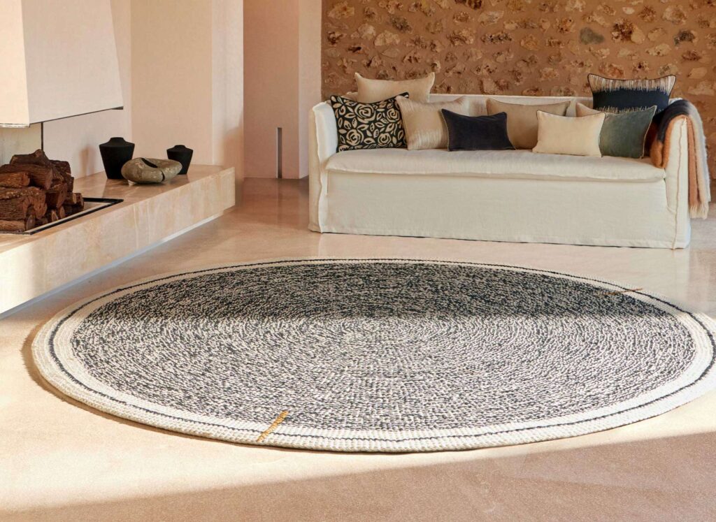 Rond Elitis vloerkleed Oscar TA 131 02 07 in een sfeervolle woonkamer met lichte bank en kussens.