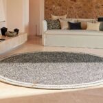Rond Elitis vloerkleed Oscar TA 131 02 07 in een sfeervolle woonkamer met lichte bank en kussens.