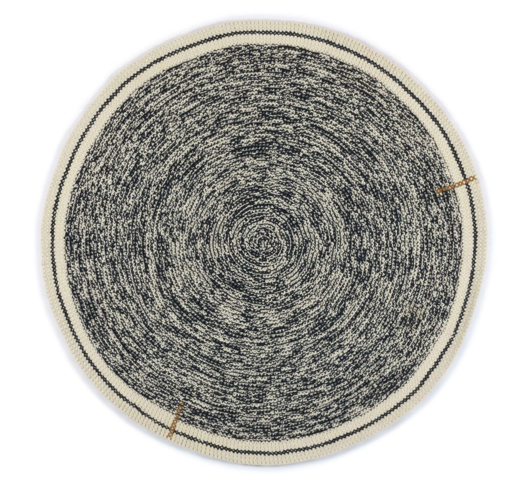 Rond Elitis vloerkleed Oscar TA 131 82 07 met een gemêleerd zwart-wit patroon en lichtgekleurde rand.