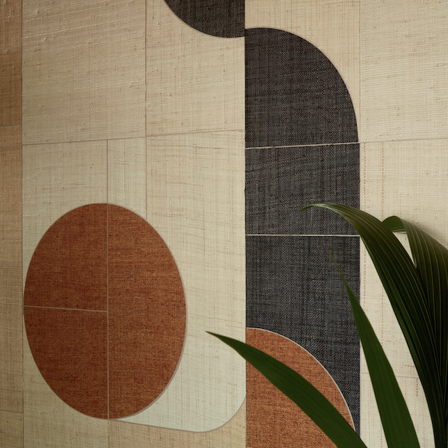 Detail van de Elitis Merida Wall Sol RM 1021-80 wandbekleding met geometrisch patroon in aardetinten en een groene plant op de voorgrond.