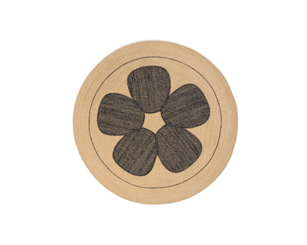 Rond buitenvloerkleed Eltis Amapola met beige ondergrond en zwart bloemenmotief.