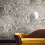 Mosterdgele fluwelen chaise longue voor een Fornasetti Nuvolette wolkenbehang met een hangende marmeren bolvormige lamp.