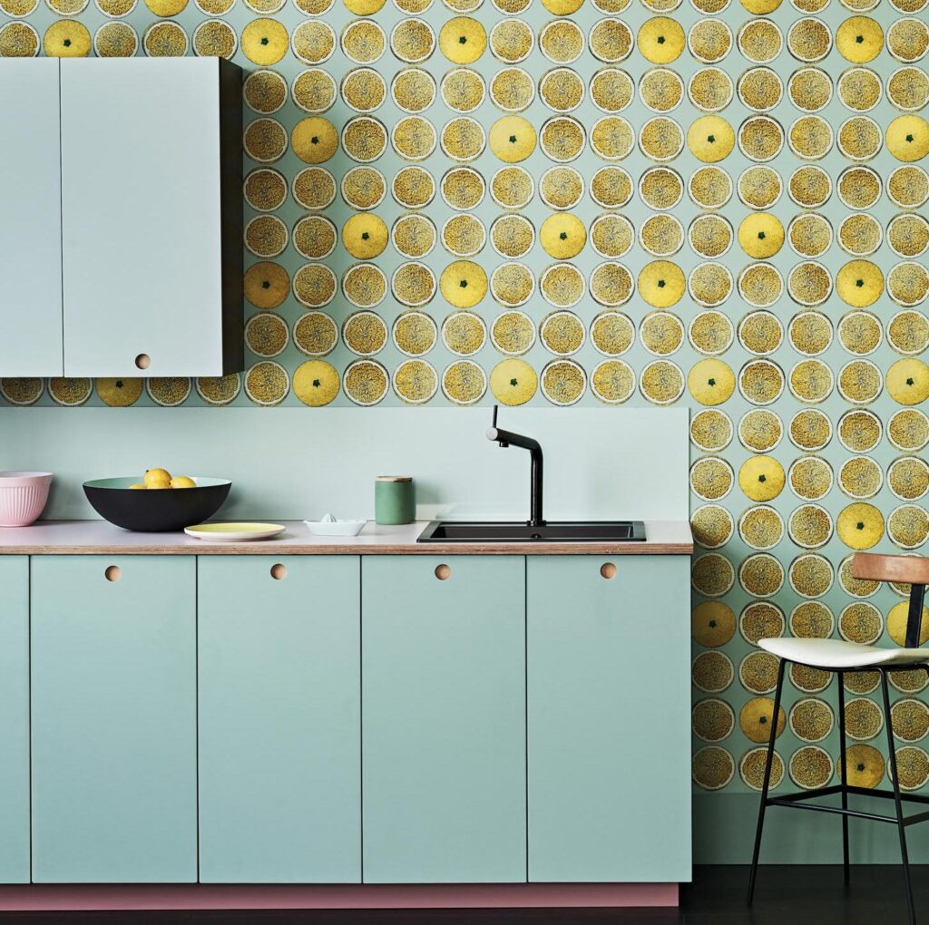 Mintgroene keuken met een achterwand van Fornasetti Senza Tempo Arance-behang met illustraties van gele sinaasappelhelften.