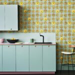 Mintgroene keuken met een achterwand van Fornasetti Senza Tempo Arance-behang met illustraties van gele sinaasappelhelften.