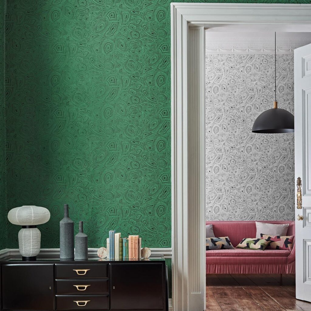 Interieur met groen Fornasetti Malachite-behang en doorkijk naar kamer met zwart-witte variant en roze bank.