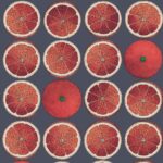 Illustratie van het Fornasetti-behang 'Senza Tempo Arance' met een patroon van rode sinaasappelschijven en hele sinaasappels op een donkerblauwe achtergrond.
