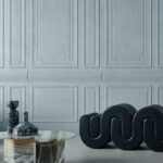 Moderne interieursetting met de Grandeur2-EXJN-2 fauteuil, een marmeren tafel en decoratieve vazen tegen een lichtgrijze, klassiek gelijnde wand.