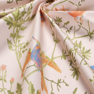 Detail van katoenen stof Hummingbirds-coton-F1253010 met kleurrijke kolibries en groene bladeren op een lichtroze achtergrond.