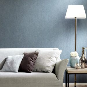Lichte zithoek met een grijze bank, sierkussens, staande lamp en decoratieve accessoires tegen een blauwe LesUnis1-PO3O muur.