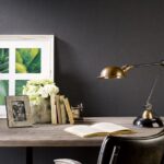Stijlvol bureau met een open boek, vintage bureaulamp, bloemenvaas en ingelijste kunst uit de LesUnis6-MVIC serie.