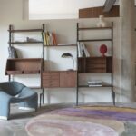 Moderne woonkamer met een Limited Edition Agate High Malaga wandkast, een blauwe designstoel en een rond vloerkleed in pastelkleuren.