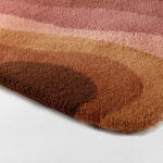 Detail van het Limited Edition Allegro Low Aprico Brandy tapijt met golvende patronen in warme bruintinten en roze.