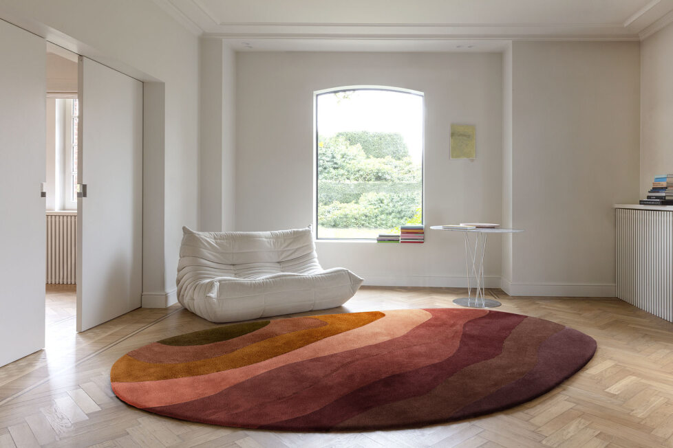 Rond vloerkleed in aardetinten uit de Limited Edition Allegro Low Aprico Brandy collectie in een minimalistisch ingerichte woonkamer.