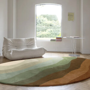 Ronde Limited Edition Allegro Low Honey Pesto vloerkleed met aardetinten in een minimalistisch interieur met een witte lounge stoel en een ronde bijzettafel.