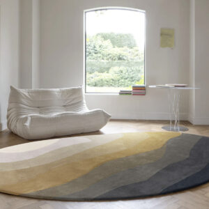 Moderne woonkamer met een rond, golvend gekleurd vloerkleed Limited Edition Allegro Low Neutral Gold Organic op een houten visgraatvloer.