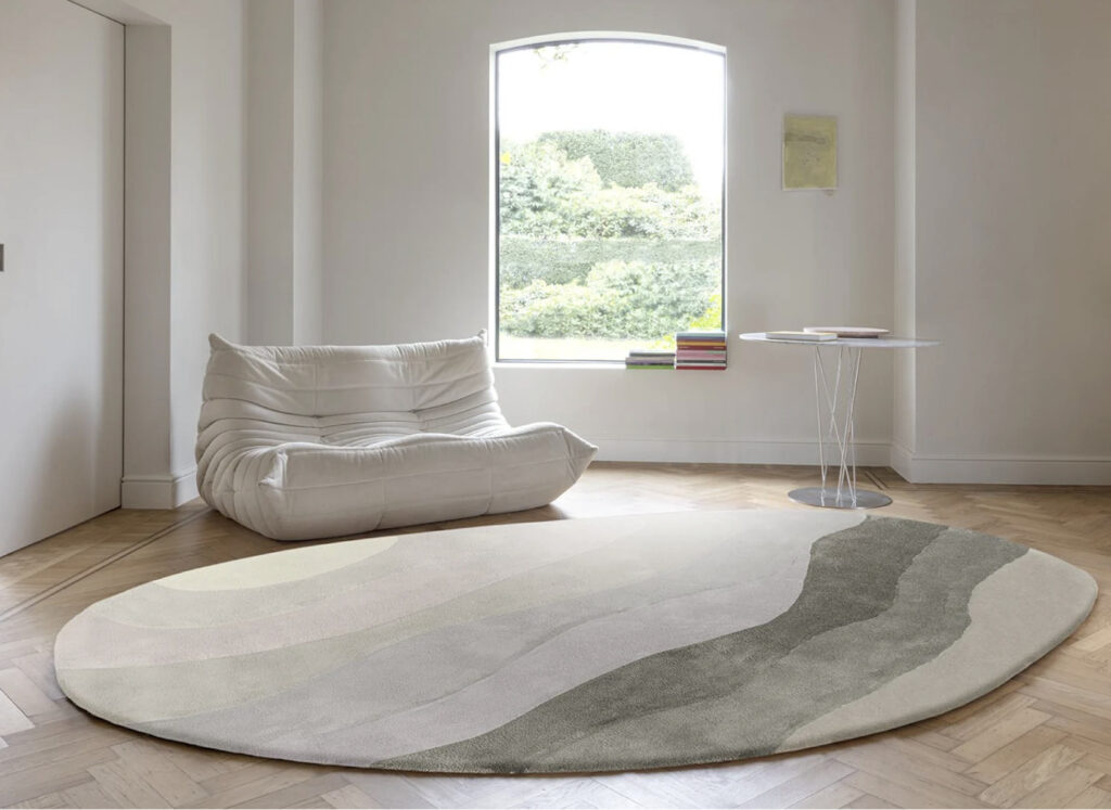 Moderne woonkamer met een organisch gevormd, rond Allegro Low Pelican vloerkleed in zachte natuurtinten.