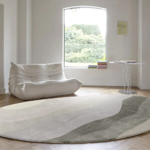 Moderne woonkamer met een organisch gevormd, rond Allegro Low Pelican vloerkleed in zachte natuurtinten.