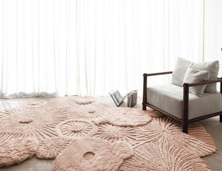 Licht ingerichte ruimte met een limited edition Atoll vloerkleed in Pale Blush en een houten loungestoel.