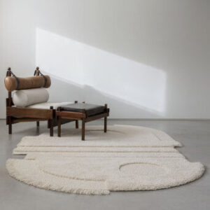 Minimalistisch interieur met een Limited-Edition vloerkleed in abstract organisch ellipsontwerp en een houten designstoel.