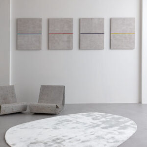 Modern interieur met het Limited Edition vloerkleed Astral White op een betonnen vloer, omringd door minimalistische stoelen en abstracte kunst aan de muur.