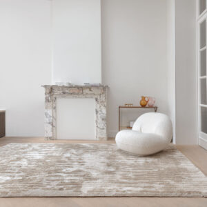 Modern interieur met het Limited Edition-vloerkleed Cosmic Vista in de kleur White Pepper voor een marmeren haard en witte designfauteuil.