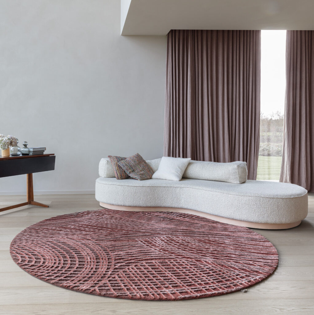 Rond vloerkleed Spiro in auburn brown in een stijlvolle, moderne woonkamer met een gebogen witte bank.
