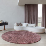 Rond vloerkleed Spiro in auburn brown in een stijlvolle, moderne woonkamer met een gebogen witte bank.