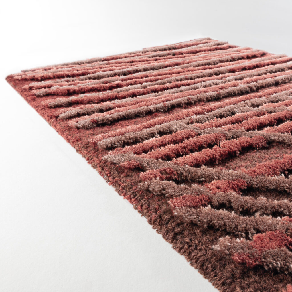 Detail van het Limited Edition vloerkleed Spiro in de kleur Auburn Brown met een textuur van verhoogde banen in rood- en bruintinten.