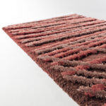 Detail van het Limited Edition vloerkleed Spiro in de kleur Auburn Brown met een textuur van verhoogde banen in rood- en bruintinten.