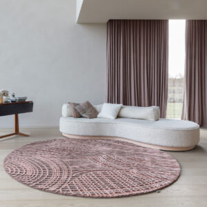 Ronde Limited Edition Spiro BrushPink vloerkleed in een moderne woonkamer met lichtgebogen witte sofa en roze gordijnen.