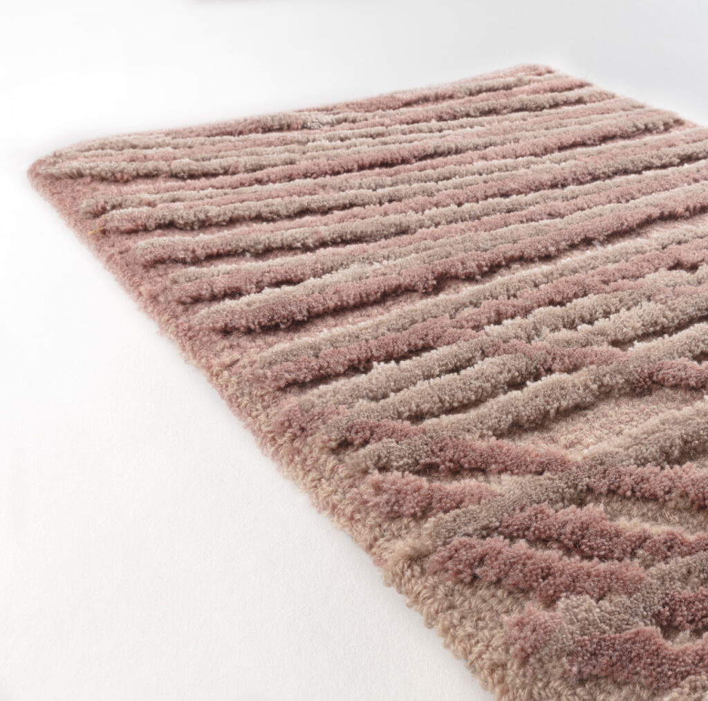 Detailopname van het Limited Edition vloerkleed Spiro in de kleur Brush Pink met een reliëfstructuur van zachte, golvende strepen.
