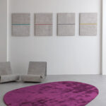 Modern interieur met paars Limited Edition-vloerkleed Astral Umber, betonnen stoelen en minimalistische wandkunst.