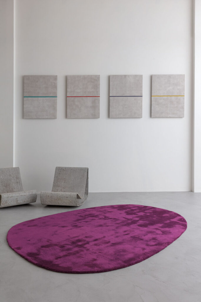 Modern interieur met paars Limited Edition-vloerkleed Astral Umber, betonnen stoelen en minimalistische wandkunst.