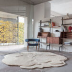 Modern interieur met het limited edition vloerkleed ‘Cosmic Cocoon Alabaster’ in organische vorm op een stenen vloer.