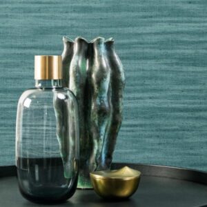 Stijlvolle opstelling met een glazen fles, organisch gevormde keramieken vaas en gouden schaaltje tegen een blauwe Lino-Lignes 40509 wandbekleding.