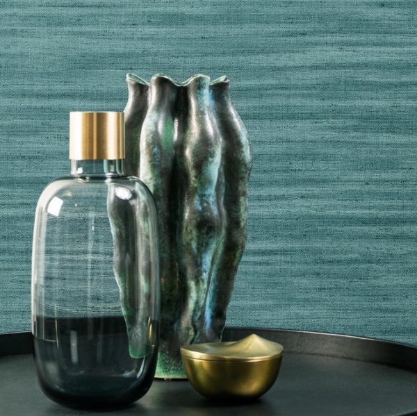 Stijlvolle opstelling met een glazen fles, organisch gevormde keramieken vaas en gouden schaaltje tegen een blauwe Lino-Lignes 40509 wandbekleding.