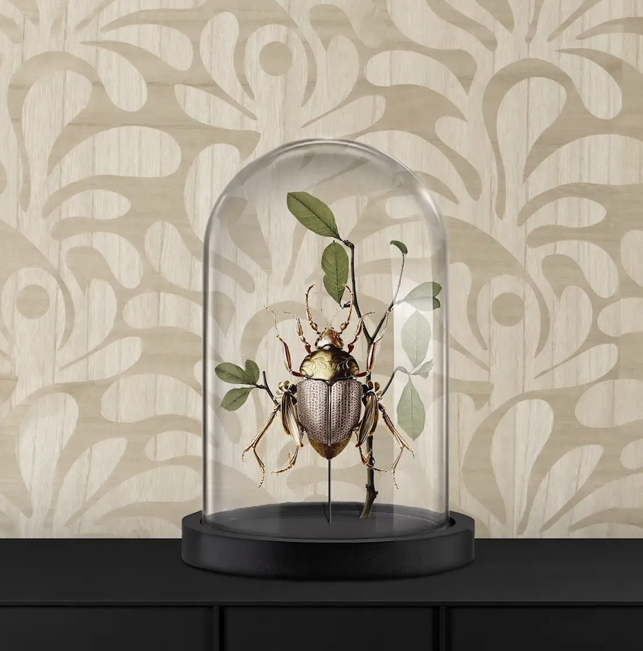 Decoratieve kever met bladeren onder een glazen stolp op een zwarte kast, tegen een beige behang met organisch patroon.