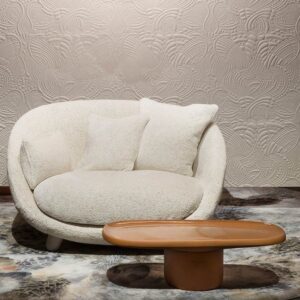 Luxe zithoek met een ronde crèmekleurige fauteuil, houten salontafel en reliëfbehang Dodo Pavone van Moooi.